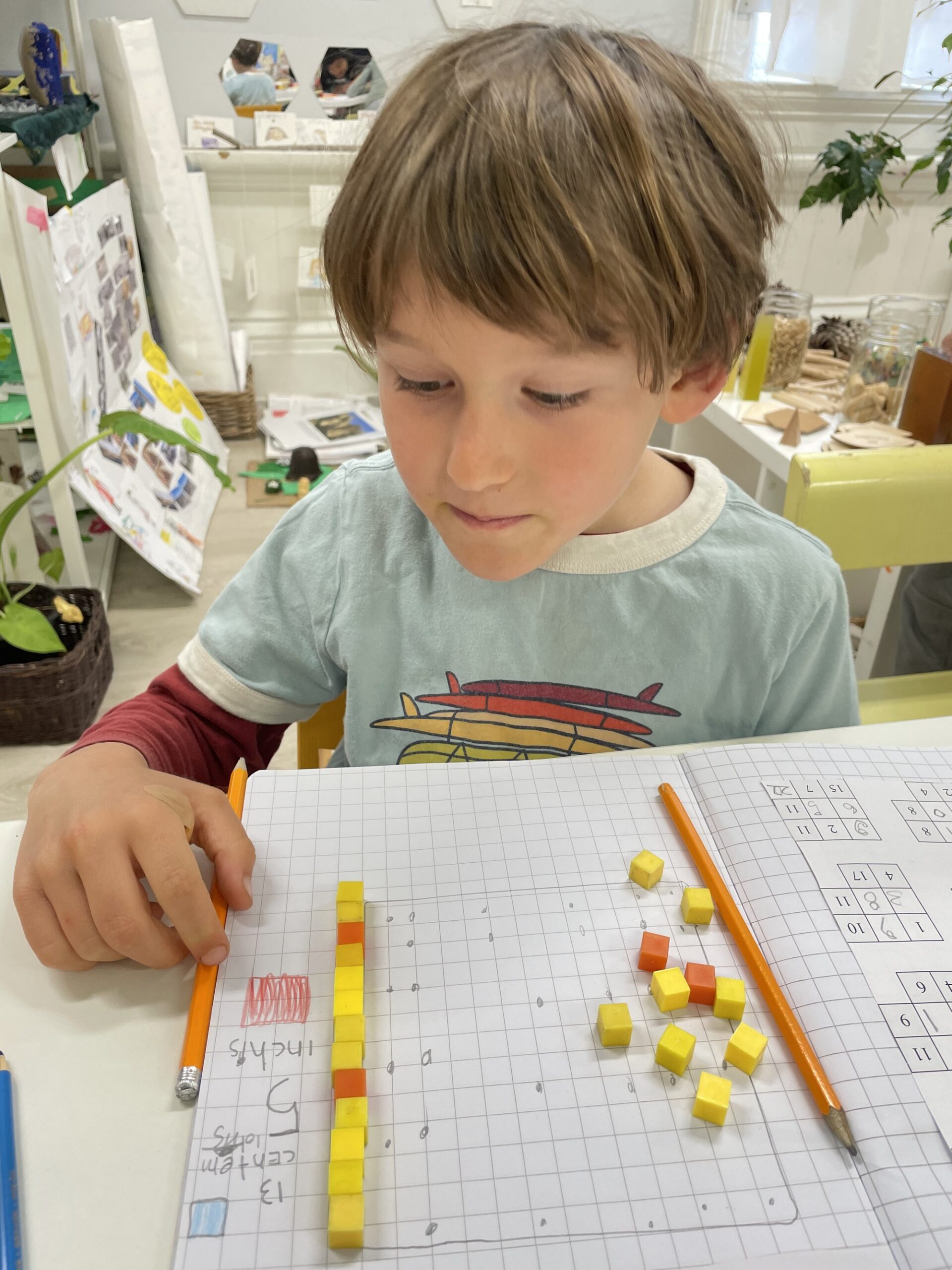 A student building number patterns with colored cubes on graph paper