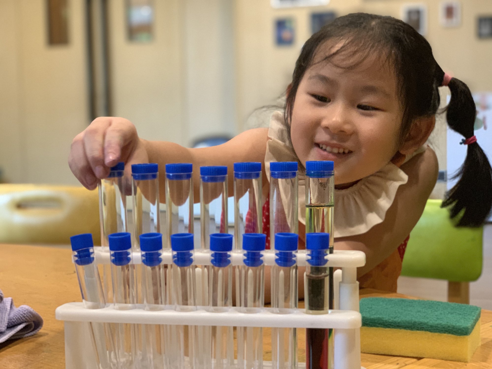 A young student filling a rack of test tubes with colored liquid