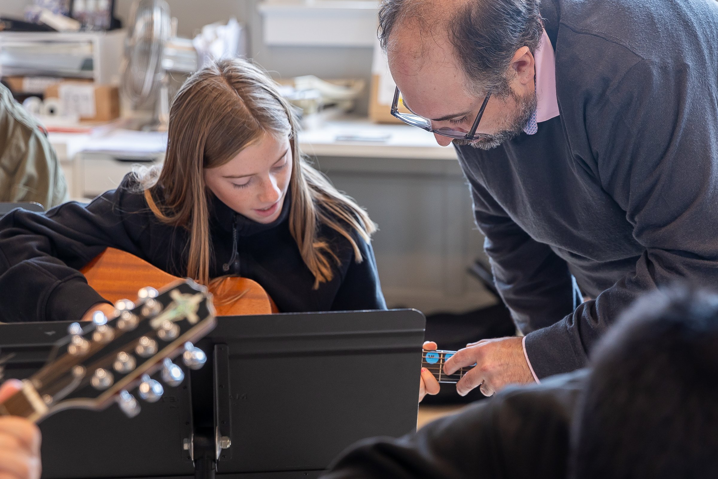 Carlo Dean, Director of Performing Arts, helping a student with a mandolin in the music room