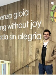“Nothing without joy — Nada sin alegría” on the wood wall, a staff member standing beside it