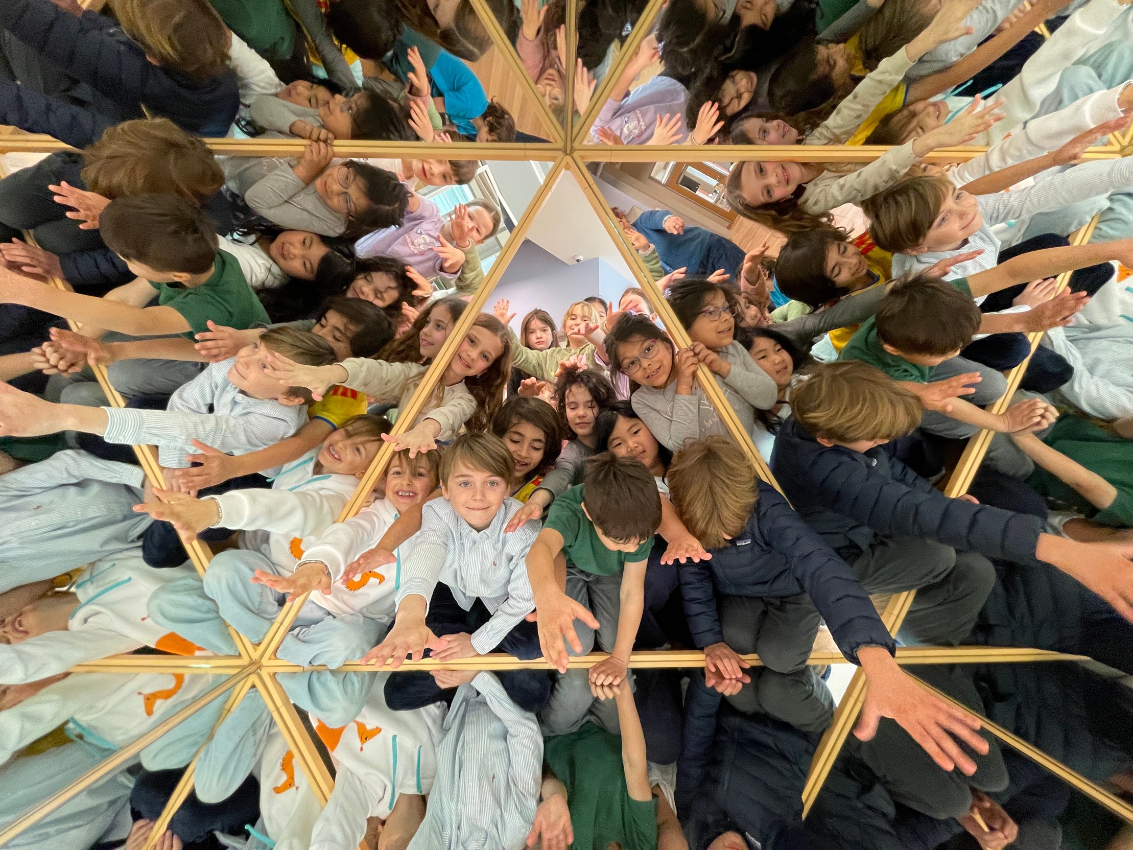 Students looking up through a wooden geometric structure, photographed from above